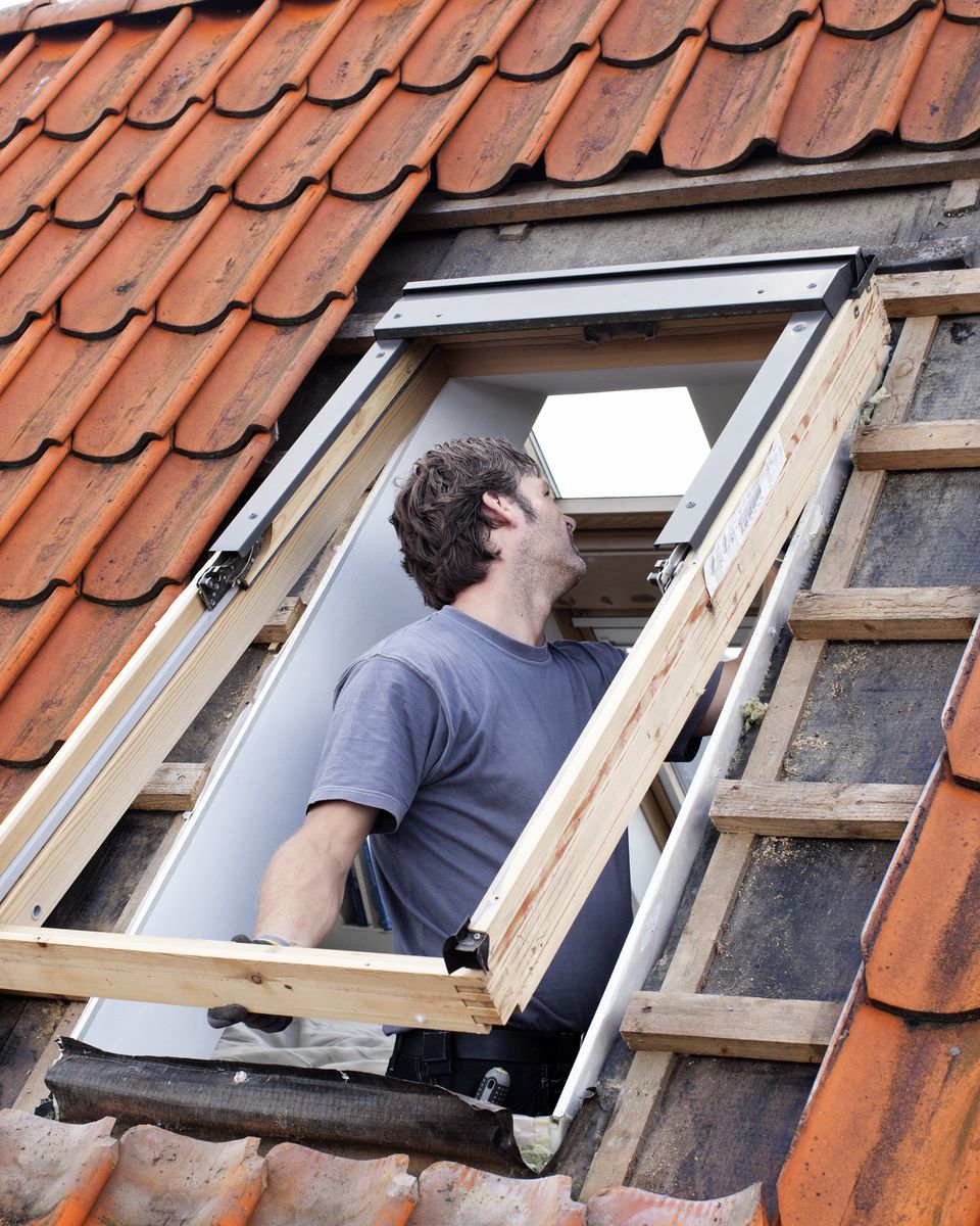 Dachdecker baut ein neues Dachfenster in ein Ziegeldach ein