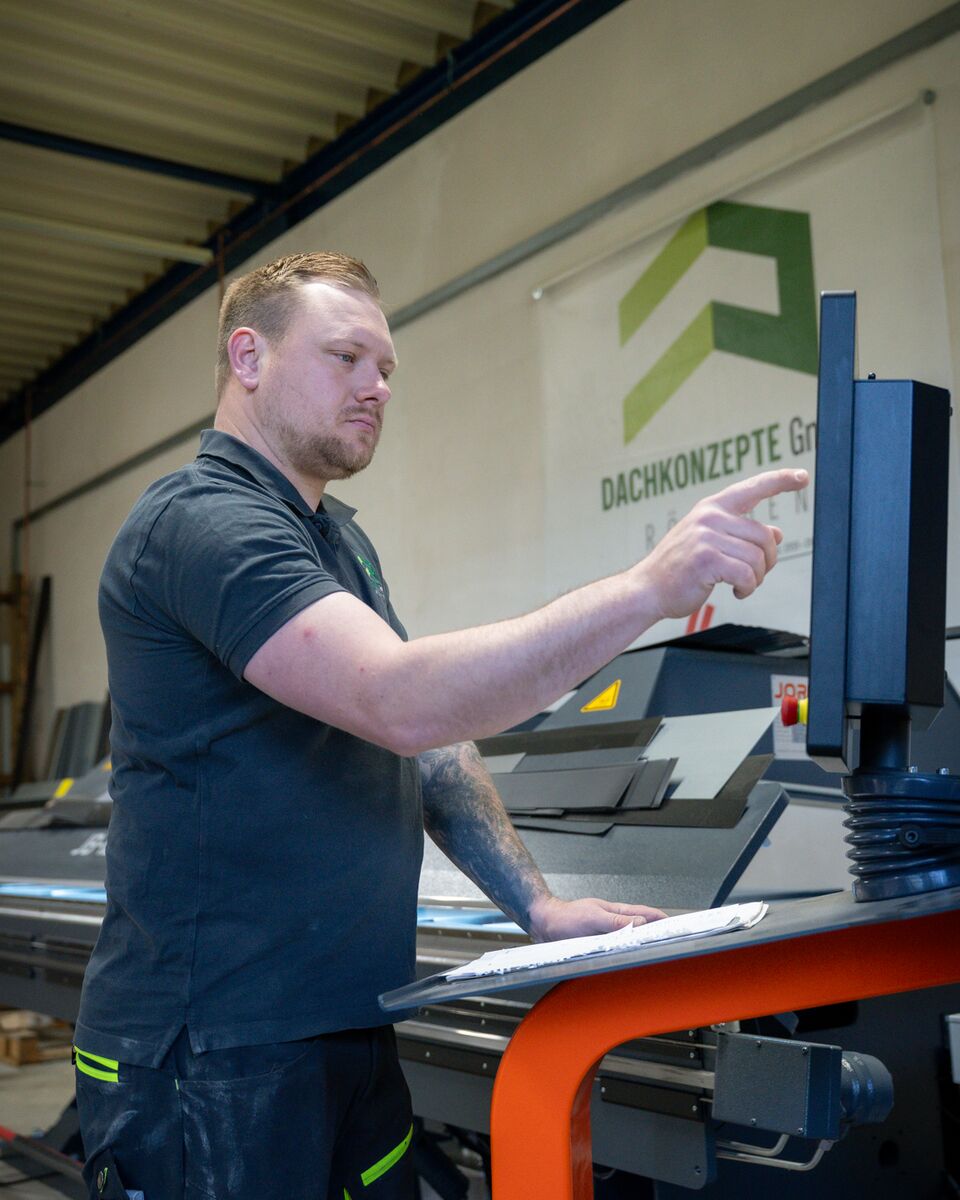 Mitarbeiter von DACHKONZEPTE programmiert die CNC-Abkantbank in der Werkhalle