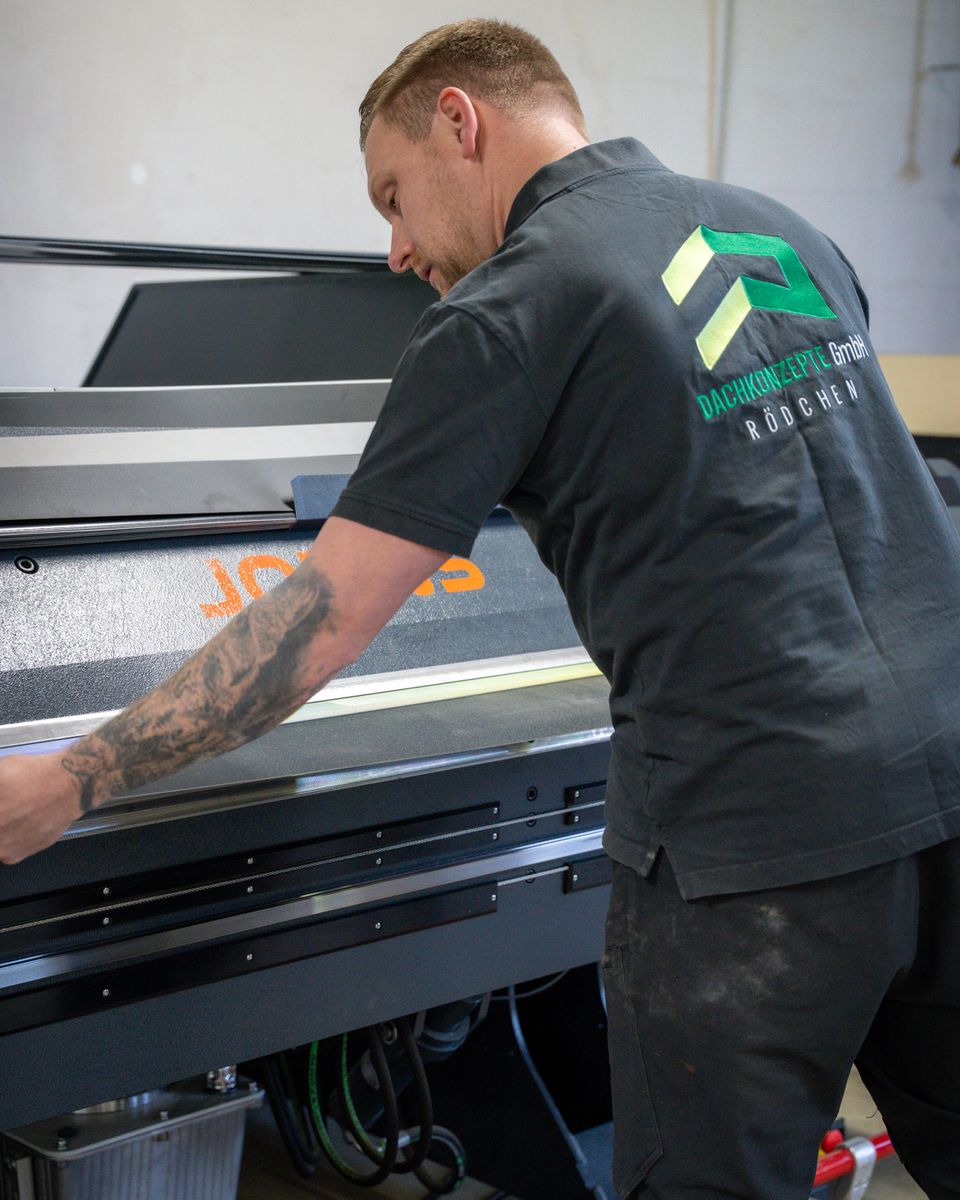 Mitarbeiter von DACHKONZEPTE legt ein Blech in die CNC-Abkantbank ein